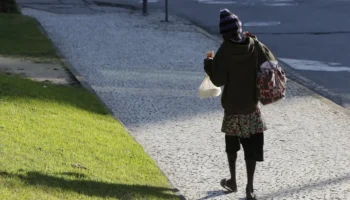 Indívíduo anda pela rua agasalhado por causa do frio