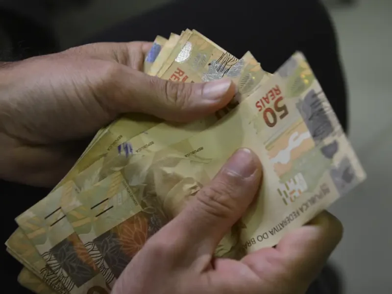 A nova regra de correção fez o governo elevar a previsão para o salário mínimo no próximo ano. O Projeto da Lei Orçamentária de 2026, enviado na noite desta sexta-feira (29) ao Congresso, prevê mínimo de R$ 1.631, R$ 1 mais alto que o valor de R$ 1.630 proposto na Lei de Diretrizes Orçamentárias (LDO). O valor representa aumento nominal de 7,44% em relação ao salário mínimo de R$ 1.518 em 2025. A alta obedece à regra aprovada no fim do ano passado, que limita o crescimento do salário mínimo a 2,5% acima da inflação do ano anterior. Pela regra atual, o salário mínimo subirá o equivalente ao Índice Nacional de Preços ao Consumidor (INPC) acumulado em 12 meses até novembro de 2025, 4,78%, mais o crescimento de 3,4% do Produto Interno Bruto (PIB, soma das riquezas produzidas no país) de 2024, o que daria valorização de 8,18%. No entanto, há um limite de crescimento de 2,5% acima da inflação, que reduz o reajuste para 7,44%. O valor final do salário mínimo em 2026 pode ficar ainda maior, caso o INPC até novembro suba mais que o esperado. Com base na inflação acumulada entre dezembro de 2024 e novembro de 2025, o governo enviará uma mensagem modificativa ao Congresso no início de dezembro.